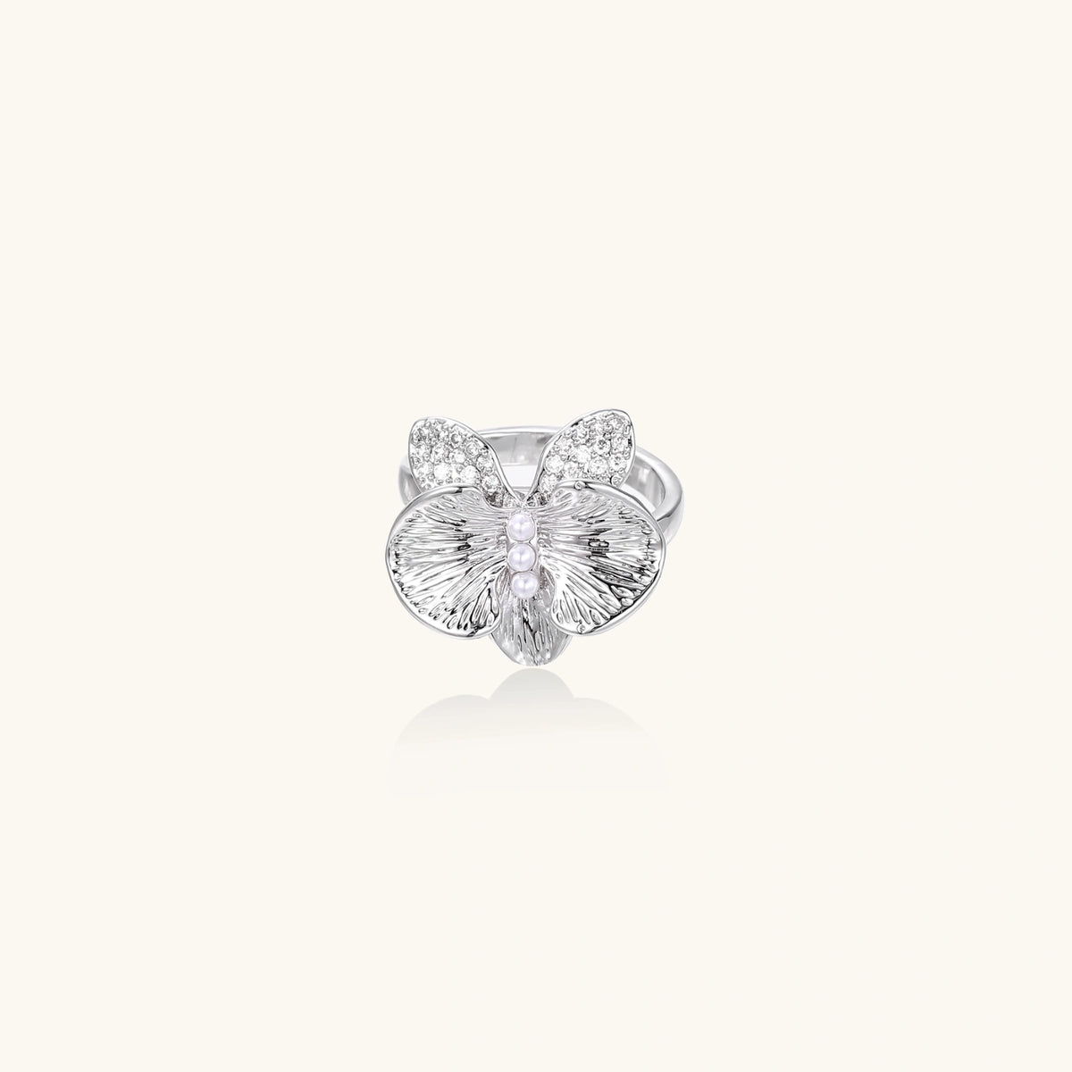 Silver-toned orchid ring with textured petals, pearl center accents, and sparkling zirconia stones on white background.