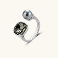 Modern adjustable ring with smoky zircon stone and metallic sphere in platinum-plated copper finish on neutral background.
